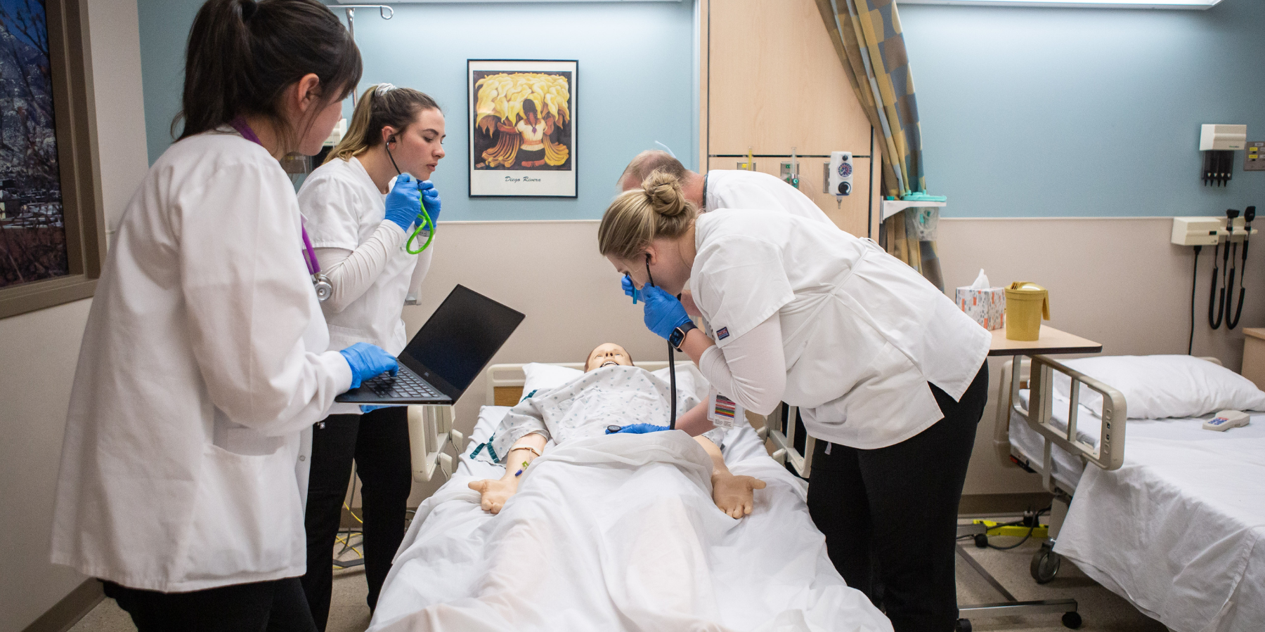 Photo of three Nursing students practicing their skills at a local hospital.