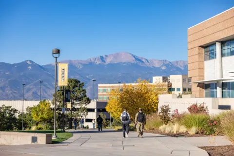military student walking on campus with mountains in the background
